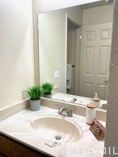 A white sink in a bathroom with a mirror above it.