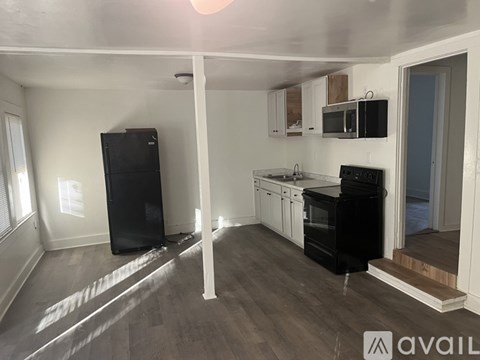 A kitchen with black appliances and wooden floors.
