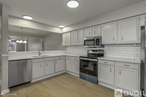 A modern kitchen with white cabinets and a wooden floor.