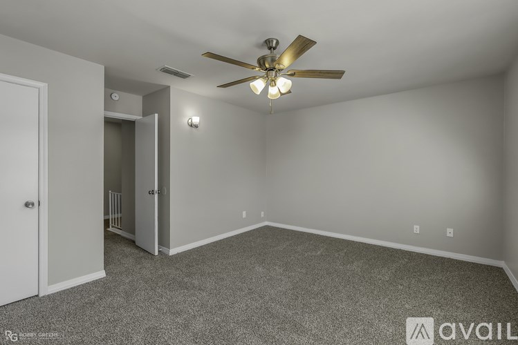 A room with a ceiling fan and carpeted floor.