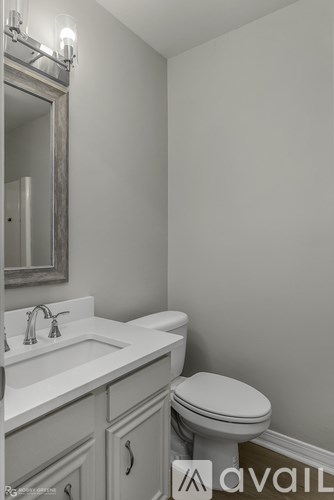 A bathroom with a toilet, sink, and mirror.