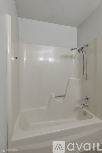 A white bathtub with a shower head and faucet.