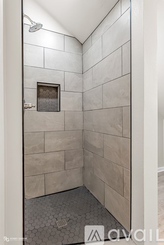 A shower area with a tiled wall and floor.