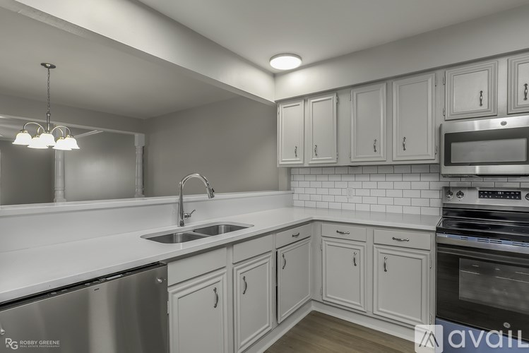 A modern kitchen with white cabinets and stainless steel appliances.