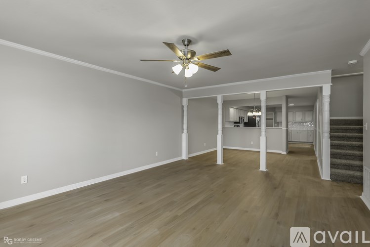 A spacious room with a ceiling fan and wooden flooring.