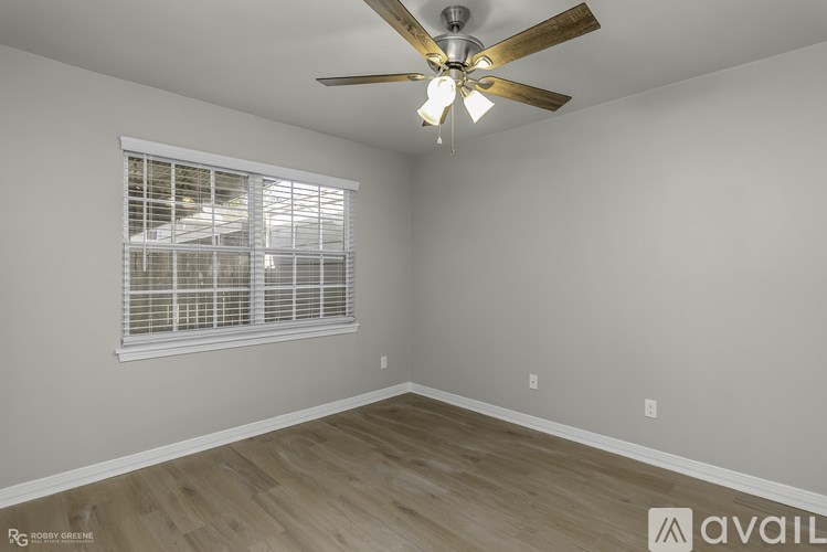 A room with a ceiling fan and a window with blinds.
