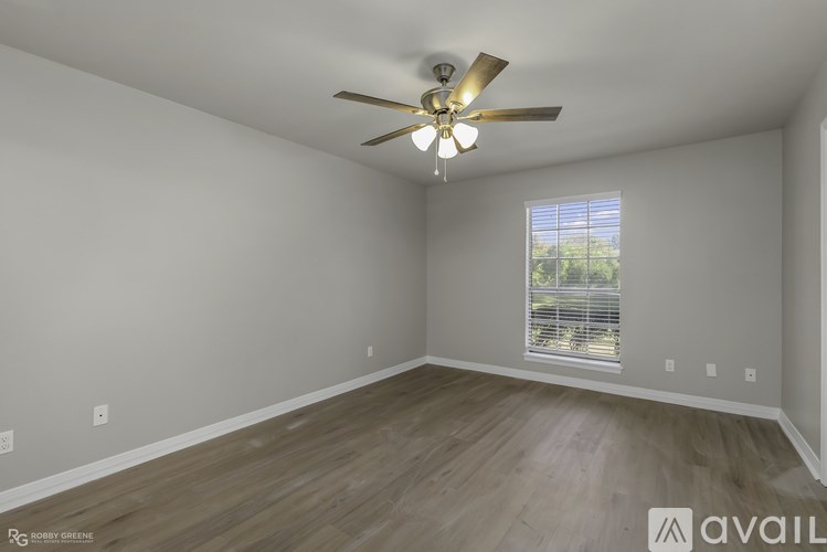 A room with a ceiling fan and a window with blinds.