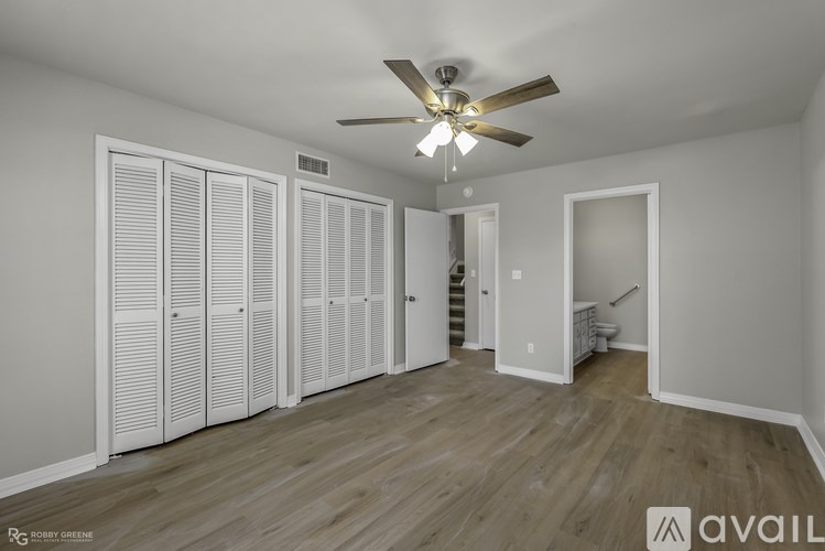 A room with a ceiling fan and wooden flooring.