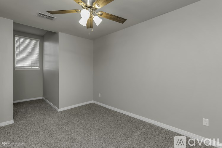 A room with a ceiling fan and carpeted floor.
