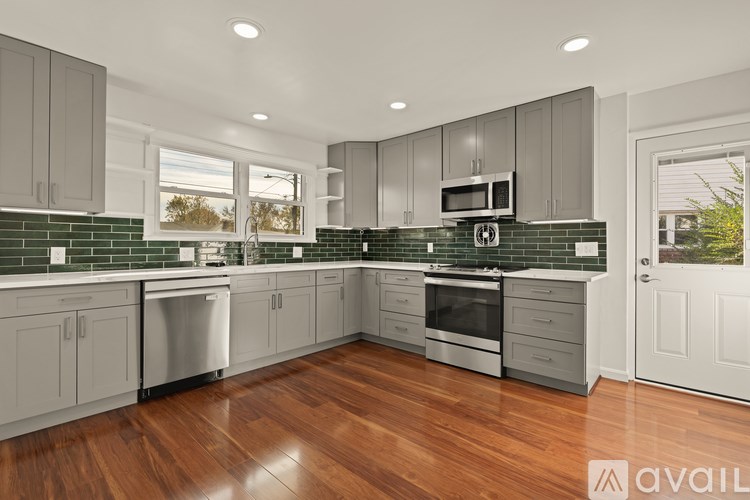 A kitchen with wooden floors and grey cabinets.