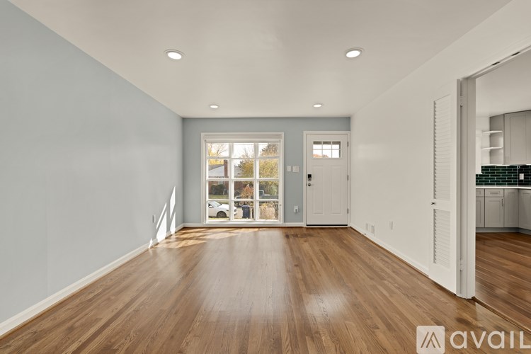 A spacious room with wooden floors and a large window.