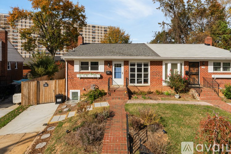 A red brick house with a front yard and a fence.