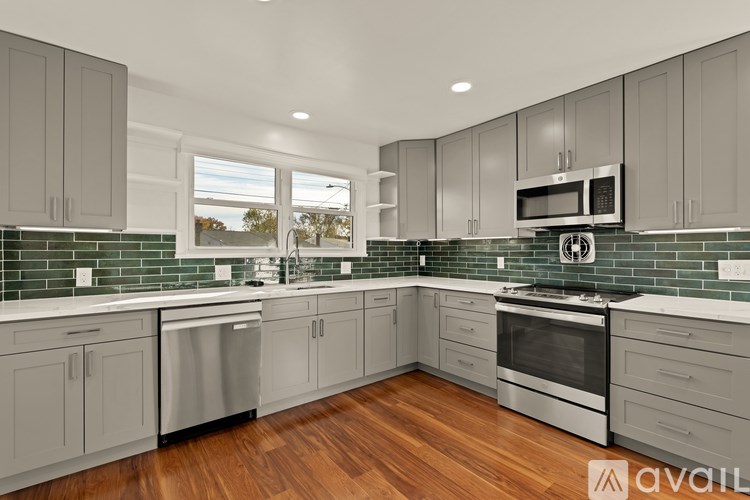 A kitchen with wooden floors and green tiles on the backsplash.