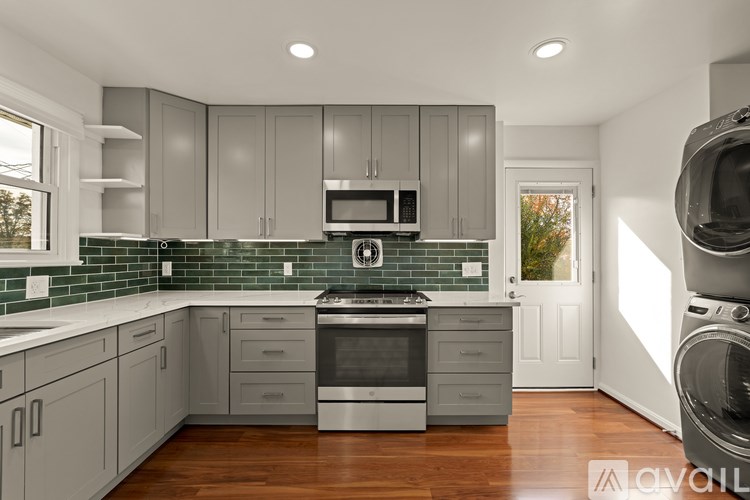 A modern kitchen with wooden floors and a green backsplash.