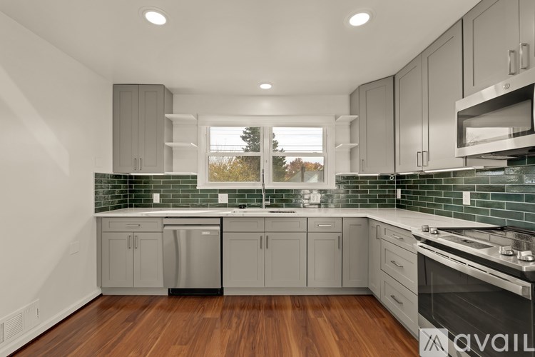 A modern kitchen with wooden floors and grey cabinets.