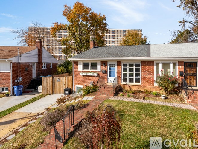 A house with a brick facade and a blue door is surrounded by a fence and a small garden.