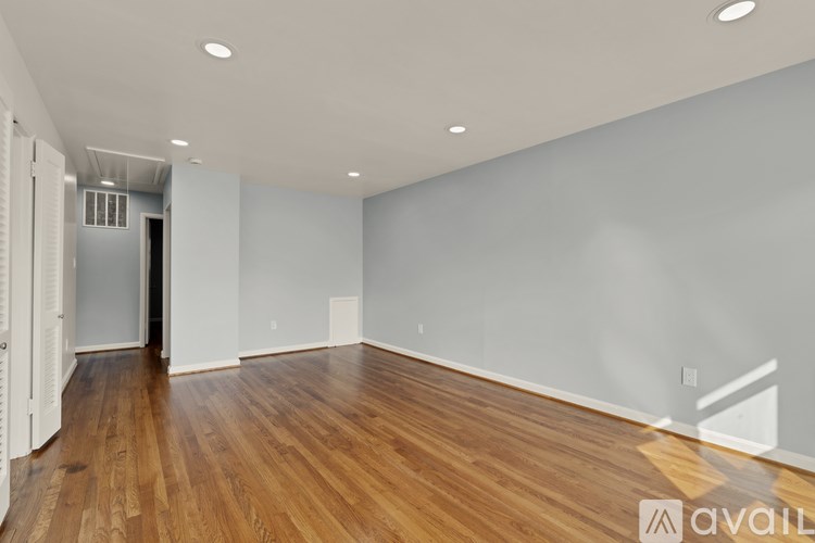 A spacious room with wooden flooring and white walls.