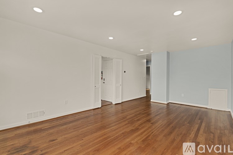 A spacious room with wooden floors and white walls.
