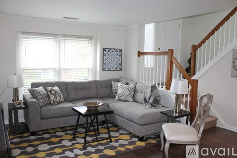 A living room with a grey couch, a coffee table, and a staircase.