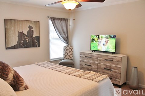 A bedroom with a bed, a dresser, a ceiling fan, and a painting on the wall.