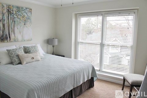 A bedroom with a large bed and a painting on the wall.