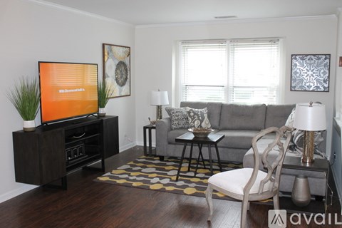 A living room with a grey couch, a wooden floor, and a television on a cabinet.