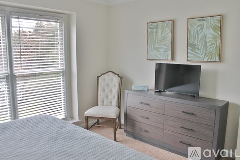 A bedroom with a bed, chair, and television.