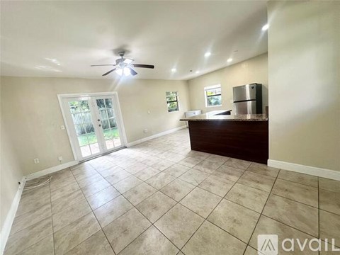 A spacious room with a ceiling fan and a kitchenette.