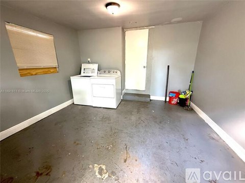 A room with a washing machine and a broom.