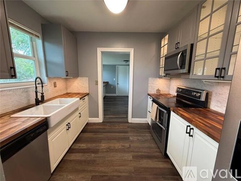 A kitchen with white cabinets and a wooden counter top.