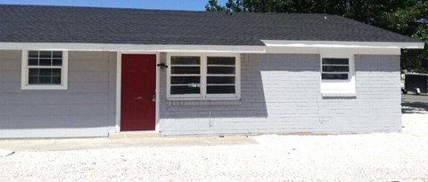 A small house with a red door and a grey siding.