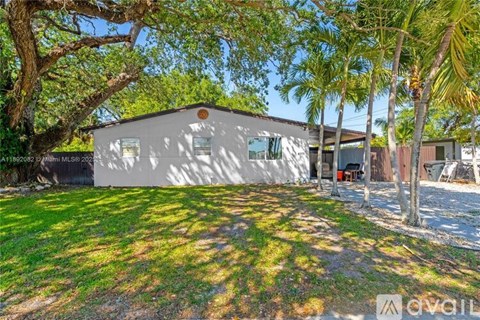 A house with a white exterior is surrounded by greenery and trees.