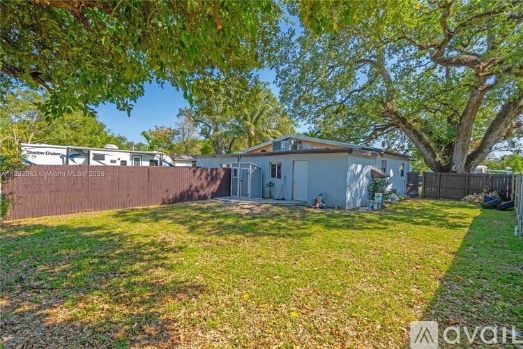 A house is for sale in a sunny, green backyard.