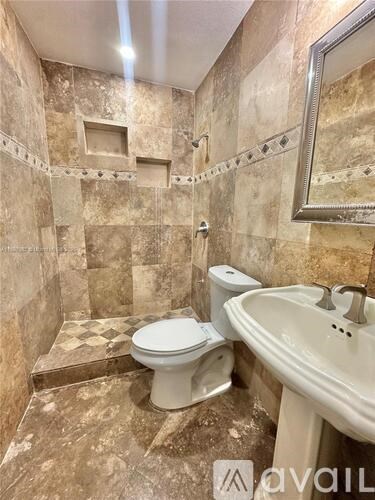 A bathroom with a toilet, sink, and tiled walls.