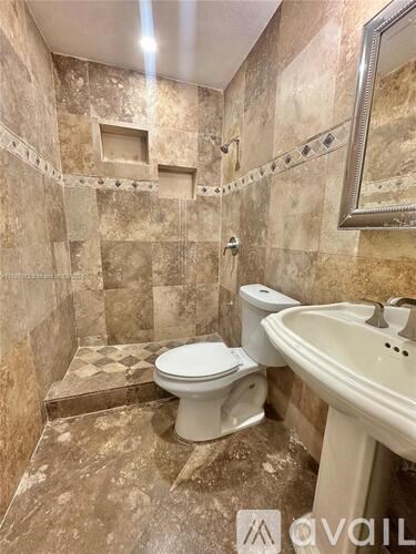 A bathroom with a toilet, sink, and tiled walls.