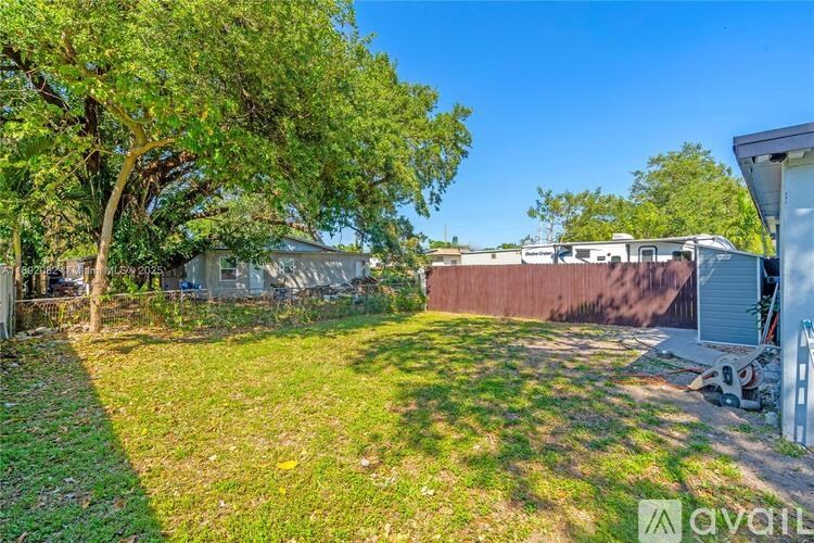 A backyard with a tree and a house in the background.