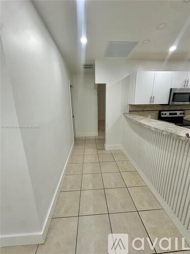 A long, narrow hallway with white walls and tiled flooring.