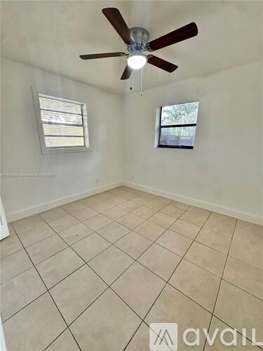A room with a ceiling fan and two windows.