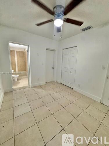 A room with a ceiling fan and tile flooring.