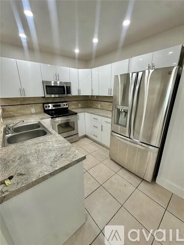A kitchen with a granite countertop and stainless steel appliances.
