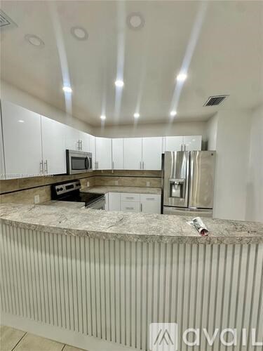 A kitchen with white cabinets and a granite countertop.