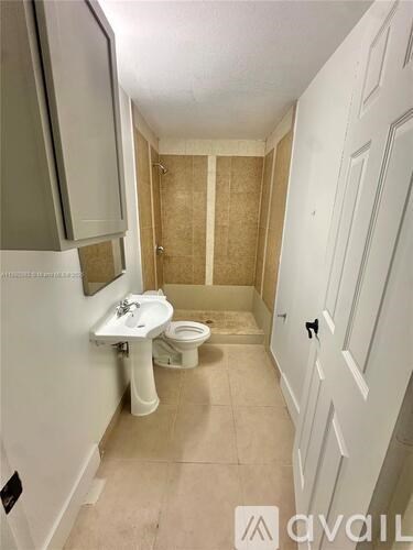 A bathroom with a toilet, sink, and cabinet.
