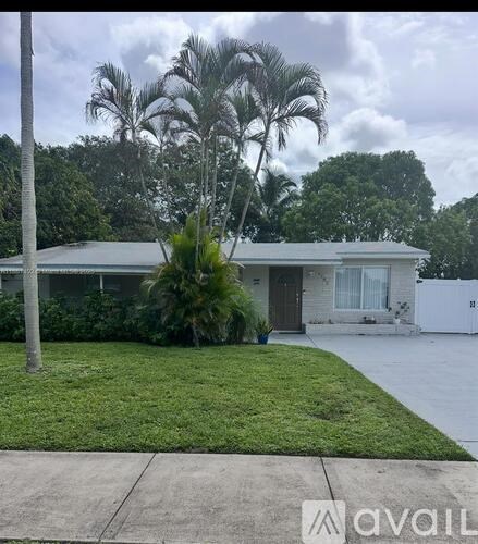 A house with a white fence and a palm tree in front.