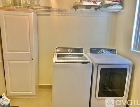A white microwave oven is placed on a white cabinet.