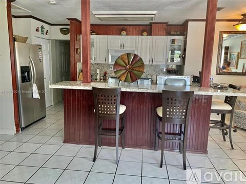 A kitchen with a bar area and chairs.