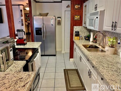 A kitchen with a granite counter top and a refrigerator.