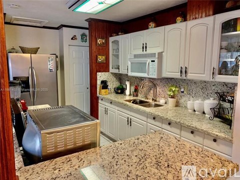 A kitchen with granite countertops and white cabinets.