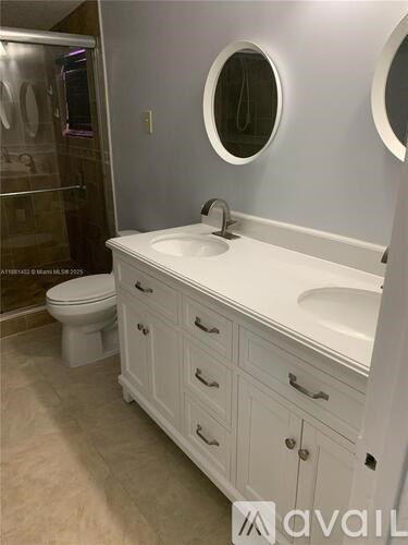 A bathroom with a white sink, toilet, and cabinets.