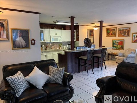 A living room with a black couch and a dining table.