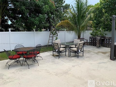 A patio with a table and chairs surrounded by a white fence.
